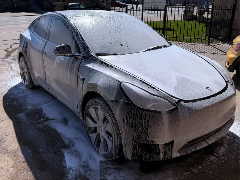 Black Tesla passenger side being washed with premium foam soap